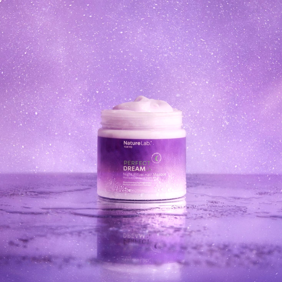 The Perfect Dream Nigh Ritual Hair Masque on a slightly reflective surface in front of a purple starry background. The jar of the masque is open to reveal the creamy, luxurious texture inside. The whole photo is cast in a purple glow.
