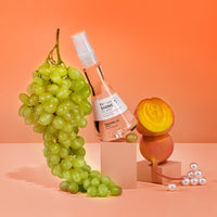 Shine Oil Mist on orange background with grapes and pearls.